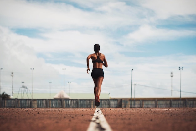 Achtergrond van een vrouwelijke atleet die op het baanveld tegen de lucht loopt