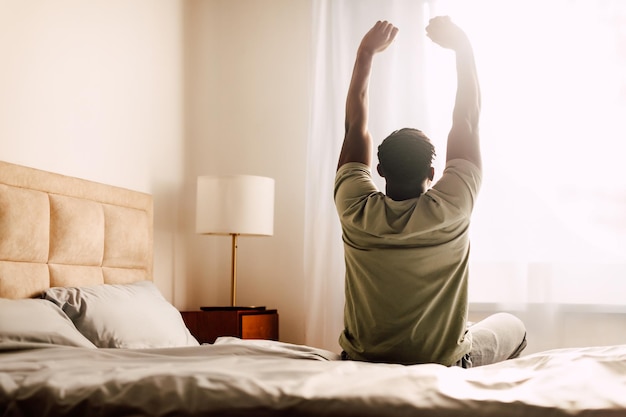 Foto achtergrond van een zwarte man die zijn armen uitstrekt in de slaapkamer