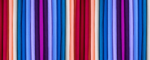 Achtergrond van gekleurde katoenen kleding. Kleuren van de regenboog. Gekleurde verticale stroken stof. Banner