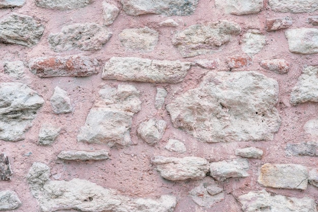 Achtergrond van het muuroppervlak is gemaakt van roze klei en witte ruwe kalksteenstenen