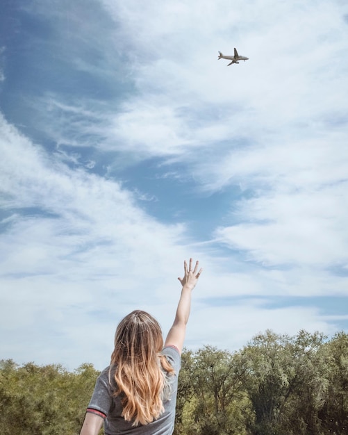 Achtergrond van vrouw die naar vliegtuig vliegt tegen de lucht