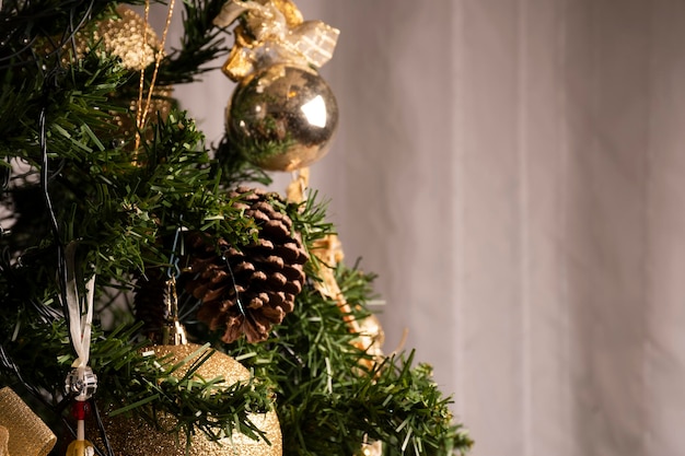 Achtergrond voor kerstkaart met close-up op kerstboom met gouden kerstballen en dennenappels en ornamenten