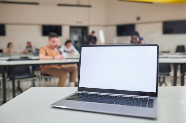 Achtergrondafbeelding van geopende laptop met leeg wit scherm op t5eachers bureau in schoolauditorium, kopieer ruimte