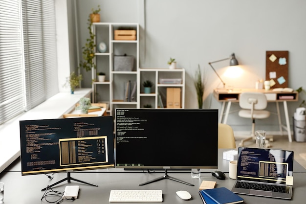 Achtergrondafbeelding van het ontwikkelaarskantoor met code op twee computerschermen en apparaten kopiëren ruimte