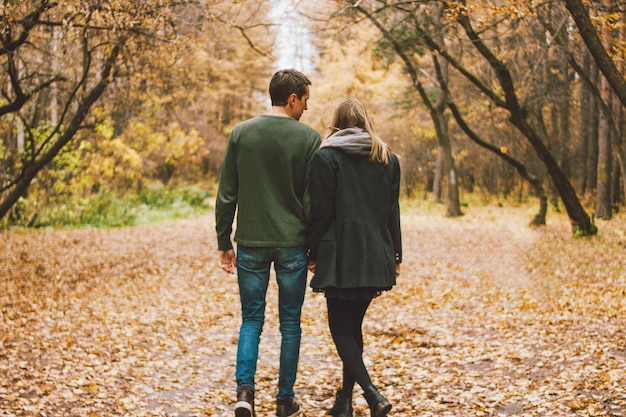 Achtergrondbeeld van een echtpaar dat in het herfstbos wandelt