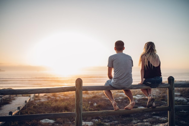 Achtergrondbeeld van een echtpaar dat op een reling tegen het strand zit
