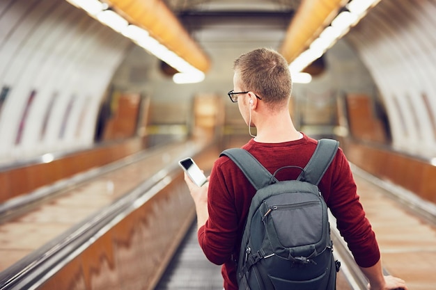 Achtergrondbeeld van een jonge man die een mobiele telefoon gebruikt terwijl hij op een roltrap staat