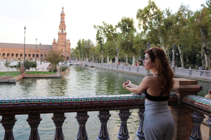 Foto achtergrondbeeld van een jonge vrouw die naar de rivier kijkt terwijl ze bij de reling tegen de lucht staat