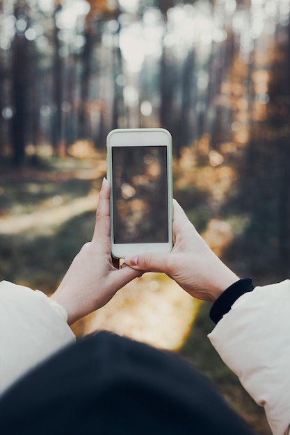 Achtergrondbeeld van een jonge vrouw die tijdens een reis foto's van een boslandschap maakt met een smartphone