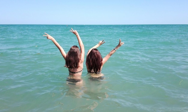 Foto achtergrondbeeld van een jonge vrouw in de zee tegen een heldere lucht