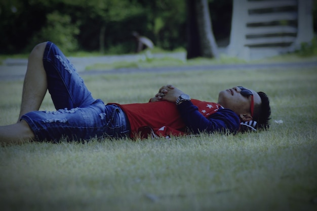 Achtergrondbeeld van een jongen die op het gras in het veld ligt