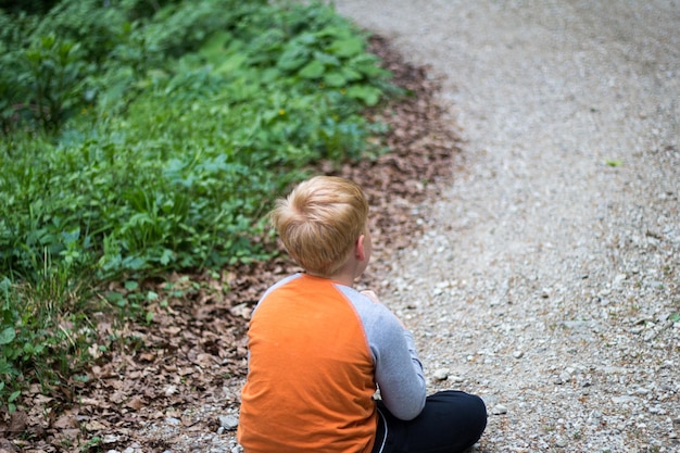 Foto achtergrondbeeld van een jongen die op het voetpad zit