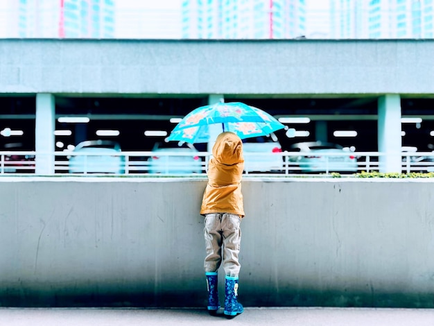 Achtergrondbeeld van een jongen met een paraplu die tegen de muur staat