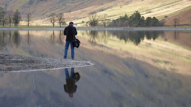 Foto achtergrondbeeld van een man die bij een meer tegen een berg staat