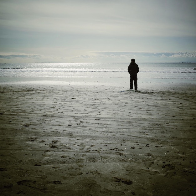 Foto achtergrondbeeld van een man die bij zonsondergang op het strand staat