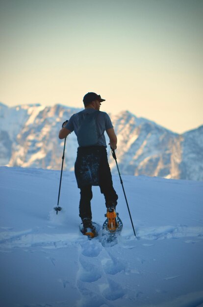 Foto achtergrondbeeld van een man die op de berg sneeuwschoenen loopt