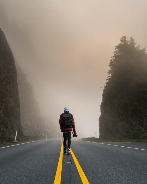 Foto achtergrondbeeld van een man die op de weg loopt tijdens mistig weer