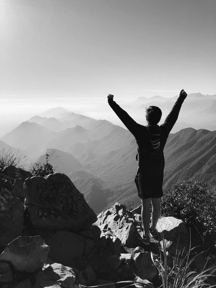 Foto achtergrondbeeld van een man die op een berg staat tegen een heldere lucht