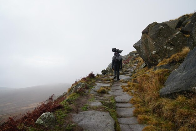 Foto achtergrondbeeld van een man die op een berg tegen de lucht loopt