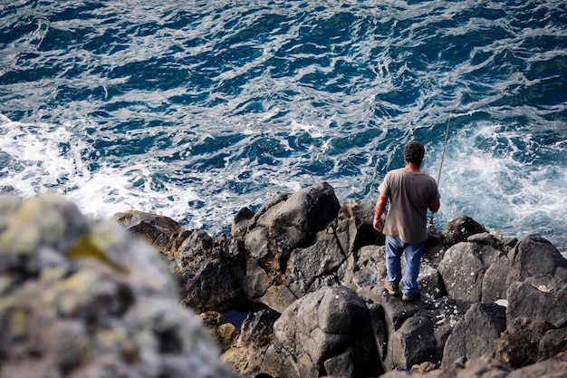 Foto achtergrondbeeld van een man die op een rots op zee staat