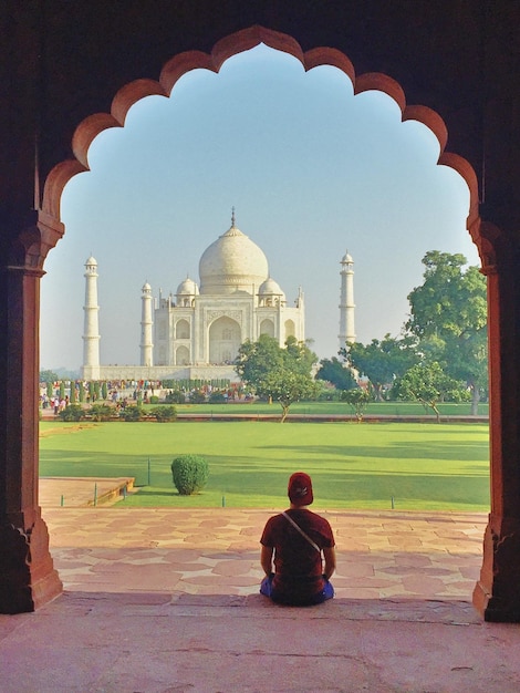 Foto achtergrondbeeld van een man die tegen de taj mahal zit