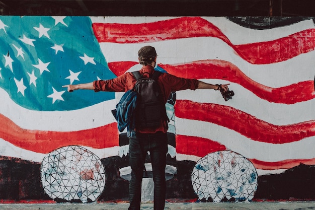 Achtergrondbeeld van een man die tegen een geschilderde Amerikaanse vlag op de muur staat