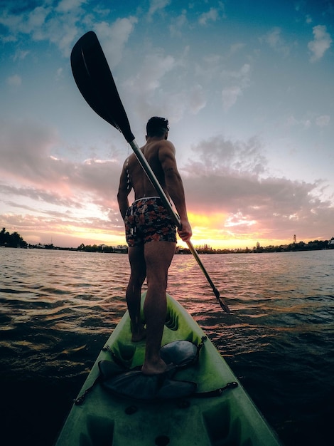 Foto achtergrondbeeld van een man die tijdens de zonsondergang op een boot tegen de lucht staat