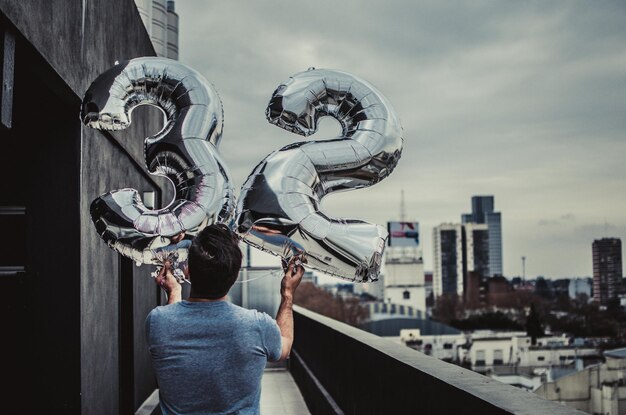 Foto achtergrondbeeld van een man met nummer 32 ballonnen op een terras in de stad