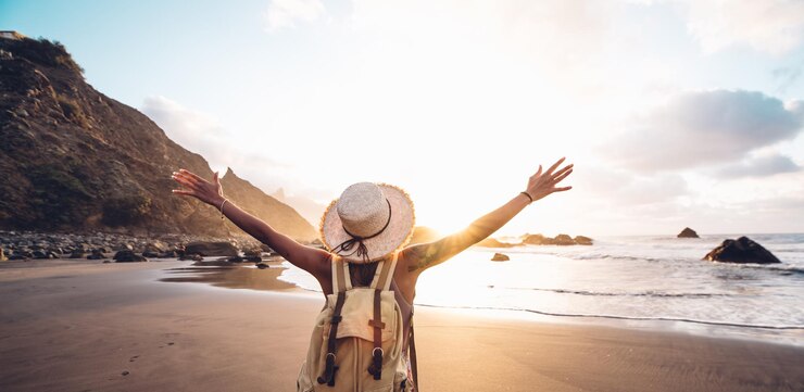 Foto achtergrondbeeld van een man met uitgestrekte armen die op het strand tegen de lucht staat