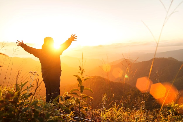 Achtergrondbeeld van een man met uitgestrekte armen die tijdens de zonsondergang op het veld tegen de hemel staat