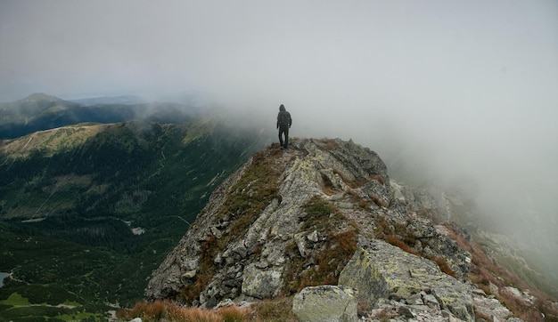 Foto achtergrondbeeld van een mannelijke wandelaar die tijdens mistig weer op de berg loopt