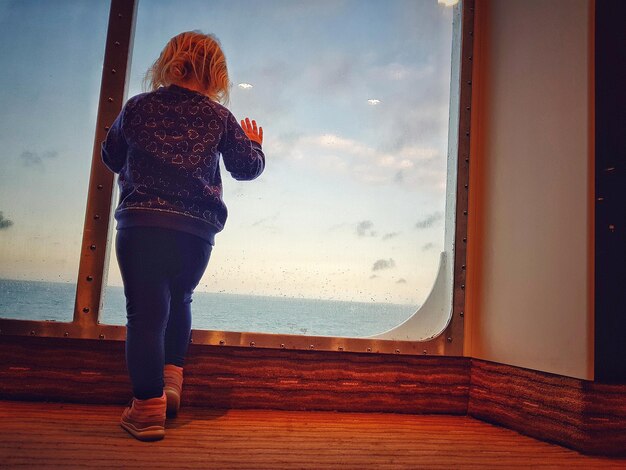 Foto achtergrondbeeld van een meisje dat in een boot tegen de zee staat