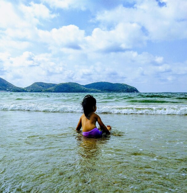 Foto achtergrondbeeld van een meisje dat op het strand zit