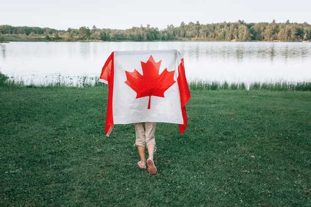 Achtergrondbeeld van een meisje met een Canadese vlag tegen een meer