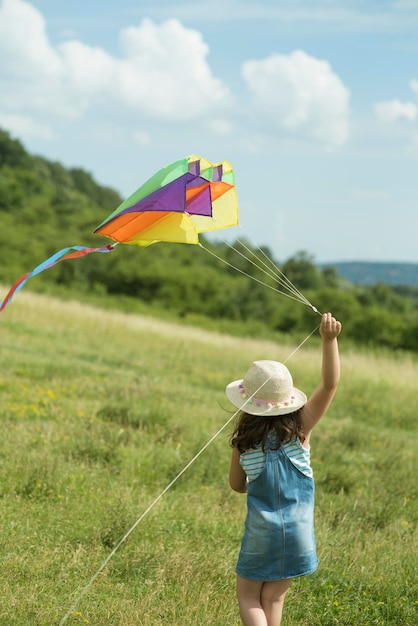 Foto achtergrondbeeld van een meisje met een vlieger terwijl ze op het veld tegen de lucht loopt