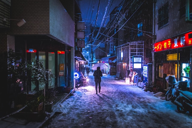 Achtergrondbeeld van een persoon die's nachts op een verlichte straat in de stad loopt