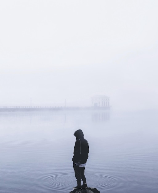 Achtergrondbeeld van een persoon die tijdens mistig weer in het meer staat