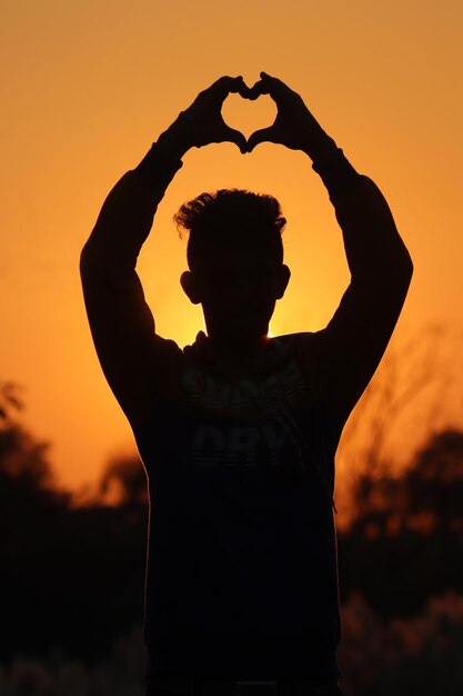 Achtergrondbeeld van een silhouet man die tegen de oranje hemel staat