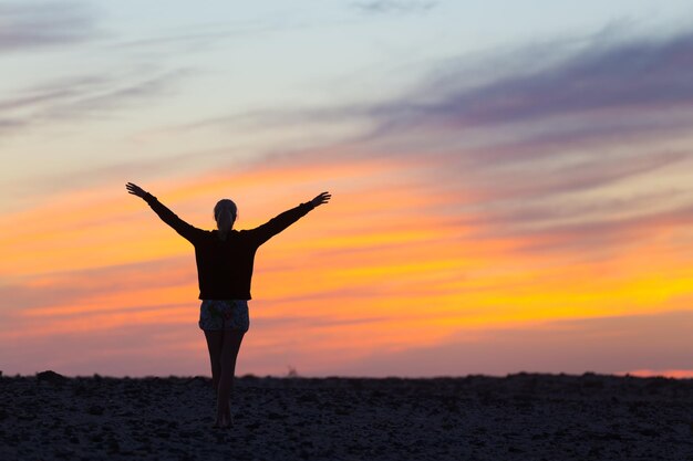 Achtergrondbeeld van een silhouetpersoon die tijdens de zonsondergang op het land tegen de lucht staat