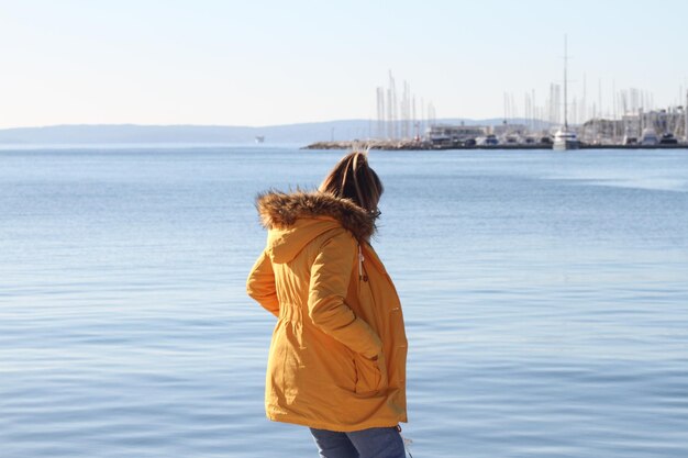 Achtergrondbeeld van een vrouw die bij de zee tegen de lucht staat