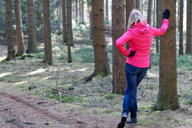 Foto achtergrondbeeld van een vrouw die bij een boom in het bos staat