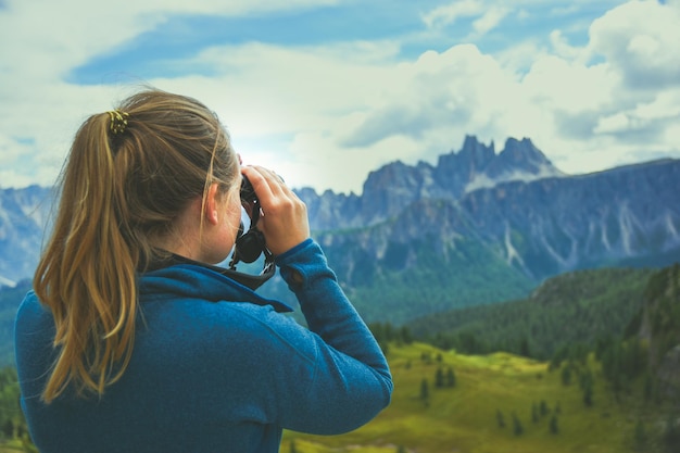 Foto achtergrondbeeld van een vrouw die door een verrekijker naar de bergketen kijkt tegen de lucht