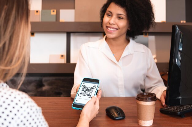 Foto achtergrondbeeld van een vrouw die een rekening betaalt via een streepjescode in een café