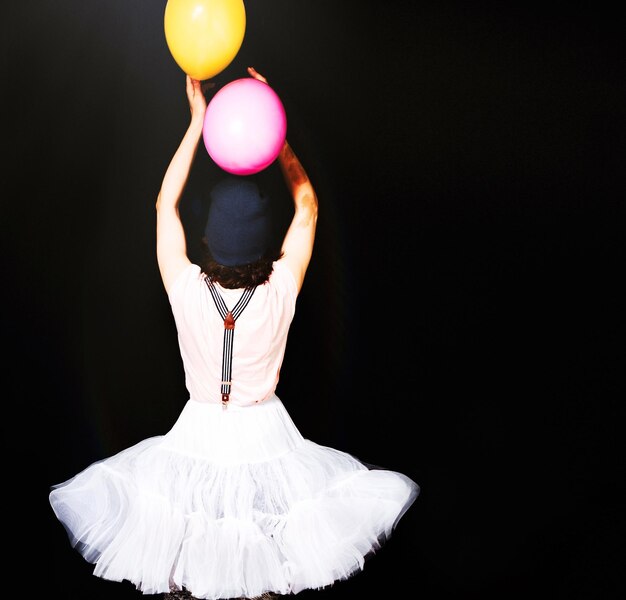 Foto achtergrondbeeld van een vrouw die een tutu draagt met ballonnen op een zwarte achtergrond