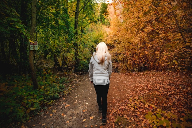 Foto achtergrondbeeld van een vrouw die in de herfst in het bos loopt