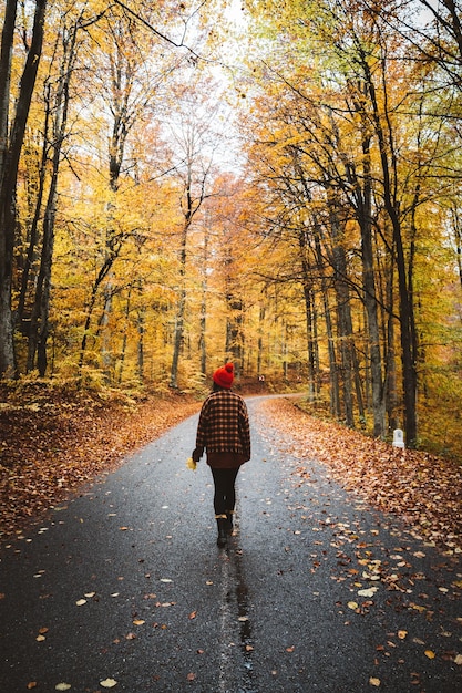 Achtergrondbeeld van een vrouw die in de herfst op de weg loopt