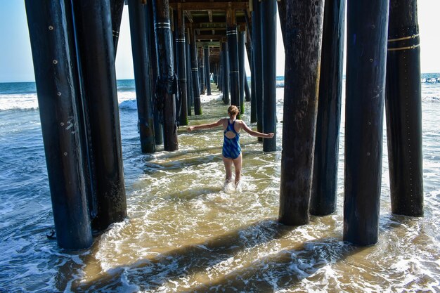 Foto achtergrondbeeld van een vrouw die onder een pier op het strand staat