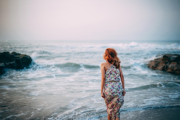Achtergrondbeeld van een vrouw die op de kust tegen de lucht staat