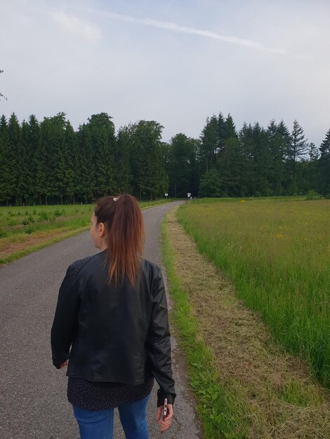 Foto achtergrondbeeld van een vrouw die op de weg loopt tegen de lucht