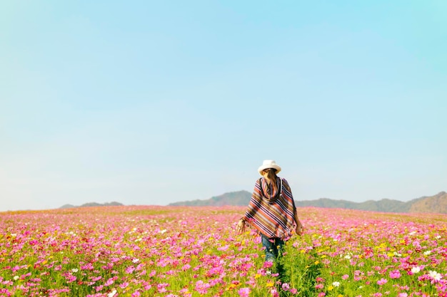 Achtergrondbeeld van een vrouw die op een bloeiend veld loopt tegen een heldere lucht
